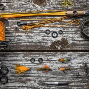 Overhead view of euro nymphing leader components arranged on weathered wood - includes Maxima Chameleon, bi-color sighter, tippet rings, fluorocarbon, tungsten beadhead nymphs, and essential tools.